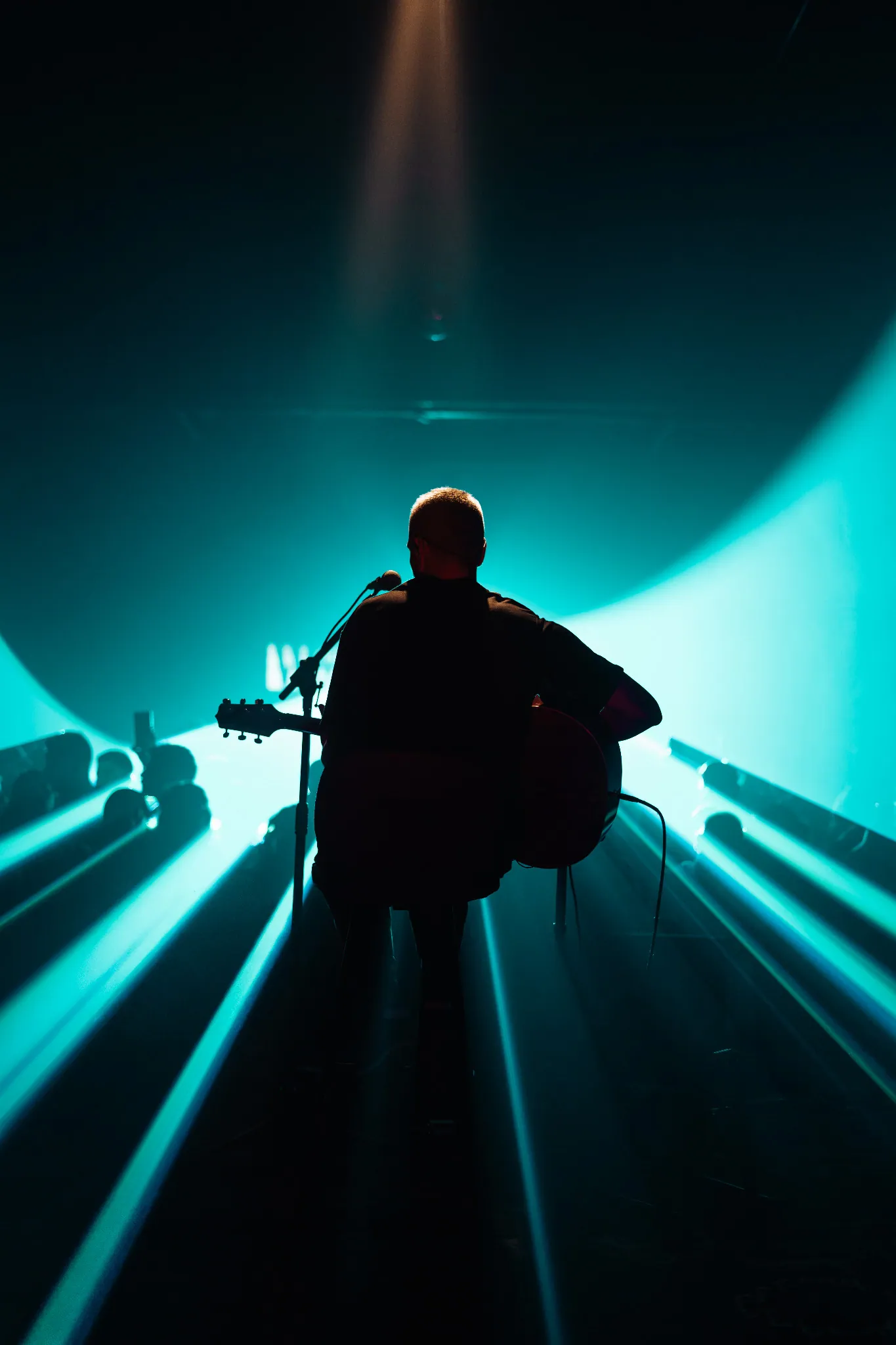Acoustic performance silhouetted against a turquoise spotlight