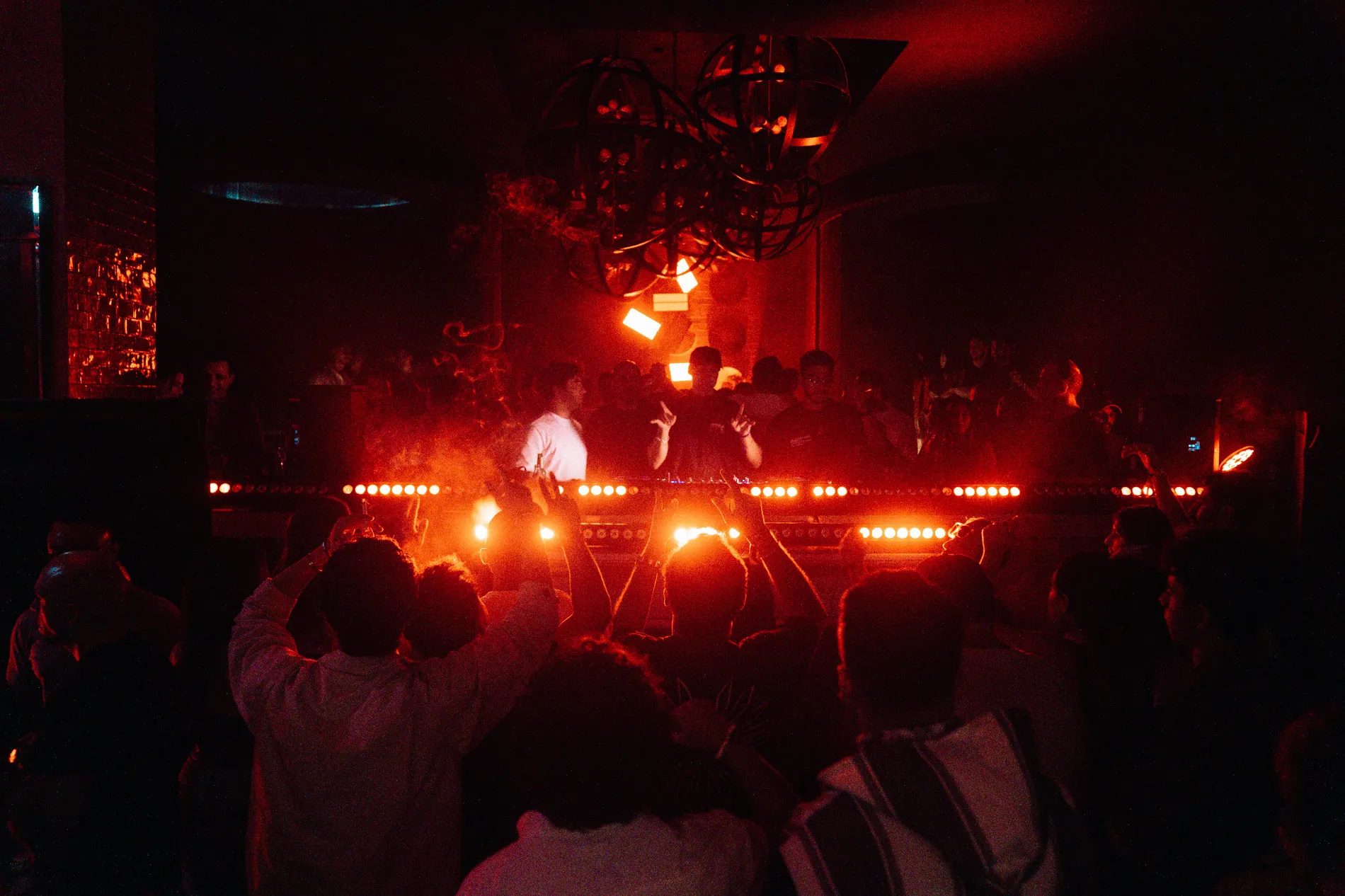 Live electronic music set with red stage lights and audience